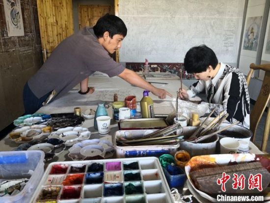 圖為2020年8月下旬，敦煌“80后”畫家張杰龍(左)在為云南麗江“學(xué)生”莫北講解敦煌壁畫的繪畫技巧?！●T志軍 攝