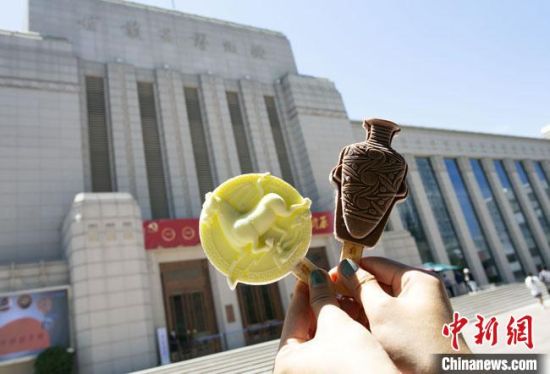 2021年7月30日，游客手拿“銅奔馬”“彩陶瓶”造型的雪糕，在甘肅省博物館前拍照打卡?！「哒?攝