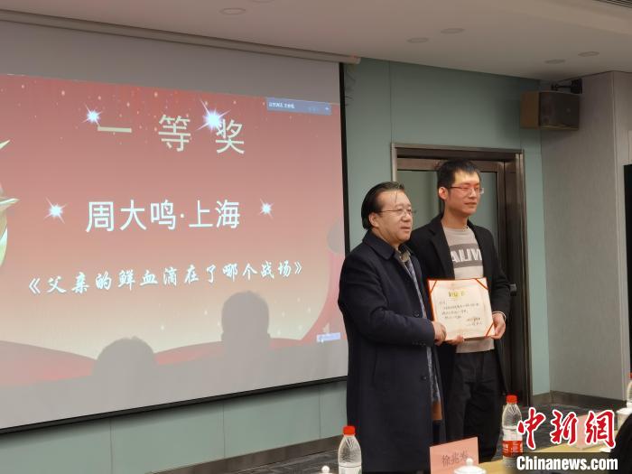 圖為作家、西北師范大學(xué)新聞與傳媒學(xué)院院長(zhǎng)徐兆壽頒發(fā)一等獎(jiǎng)證書(shū)，代領(lǐng)獎(jiǎng)?wù)呱吓_(tái)領(lǐng)獎(jiǎng)?！钅?攝