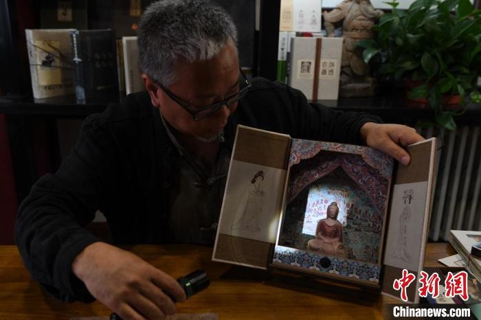 圖為讀者出版集團(tuán)讀者晉林工作室獨(dú)立出品人徐晉林，展示互動(dòng)性強(qiáng)的敦煌題材手工書(shū)。(資料圖) 楊艷敏 攝