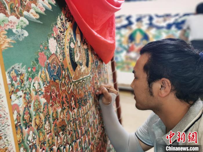 圖為更登才讓的徒弟繪畫唐卡?！?zhí)砀?攝