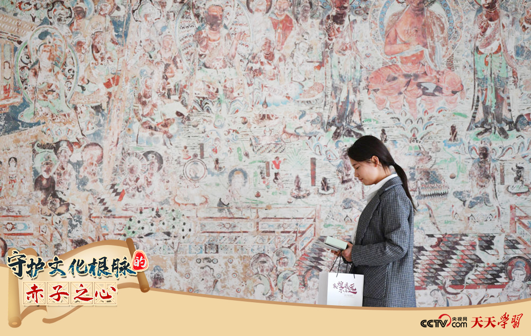 2023年4月25日，敦煌研究院文物數(shù)字化保護團隊創(chuàng)意營銷人員廖雪婷從一幅高保真復(fù)制壁畫前走過。