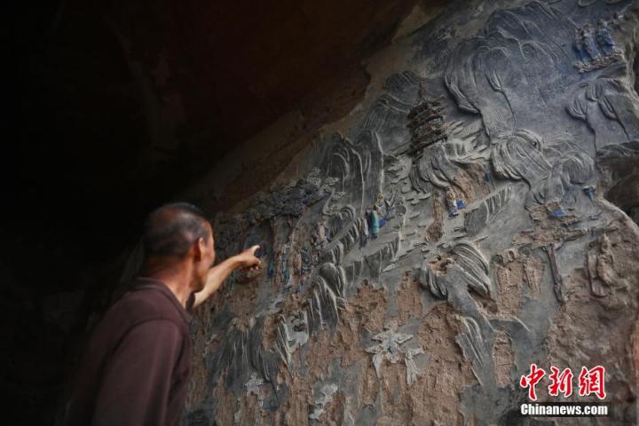 7月15日，甘肅省平?jīng)鍪袥艽h百里石窟長(zhǎng)廊羅漢洞石窟內(nèi)，該窟文保員郭建平介紹窟內(nèi)石刻彩繪壁畫。郭建平家中三代人曾自發(fā)保護(hù)羅漢洞石窟。羅漢洞石窟遺存40余個(gè)窟龕，以北魏至清代風(fēng)格為主。中新社記者 李亞龍 攝