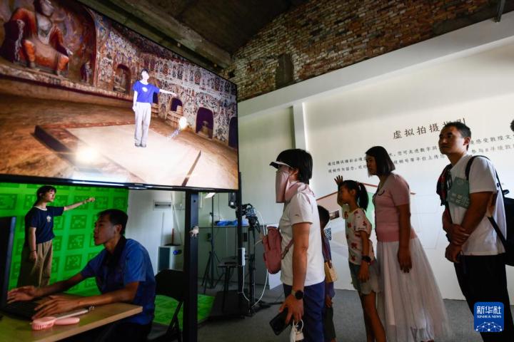7月22日，游客體驗“尋境敦煌——數(shù)字敦煌沉浸展”后，在虛擬演播廳拍攝一段真人與洞窟虛擬場景交互的視頻。新華社記者 郎兵兵 攝</p>
<p>