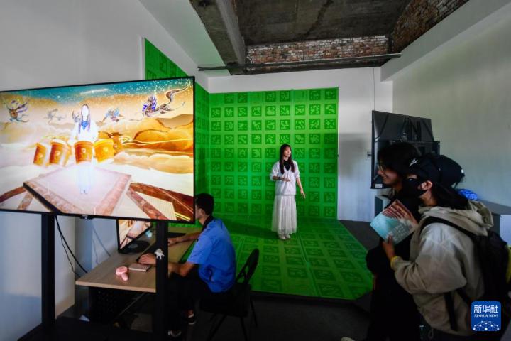 7月22日，游客體驗“尋境敦煌——數(shù)字敦煌沉浸展”后，在虛擬演播廳拍攝一段真人與洞窟虛擬場景交互的視頻。新華社記者 郎兵兵 攝</p>
<p>